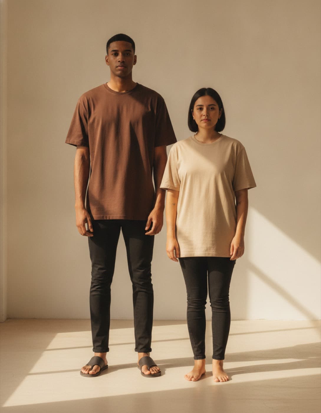Dos personas de estaturas distintas con la misma camiseta oversize, una chocolate y otra beige